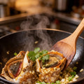 Conch meat stir-fried with herbs in a cooking pot