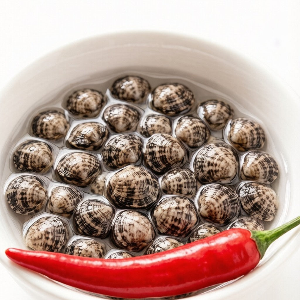 Raw speckled coquina clams in a bowl with red chilli